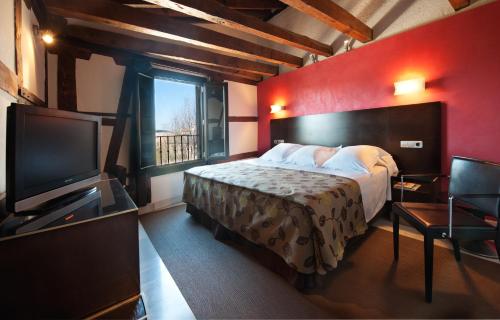 a bedroom with a large bed and a television at Pintor El Greco in Toledo