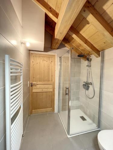 a bathroom with a shower and a wooden door at Chalet L'Argentière in La Toussuire