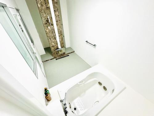 La salle de bains est pourvue d'un lavabo blanc et d'une fenêtre. dans l'établissement One Style, à Naha