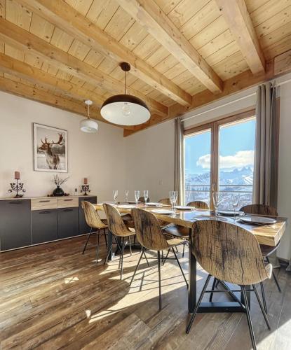a dining room with a table and chairs and windows at Chalet Le Mauntenrojji - skis aux pieds in La Toussuire