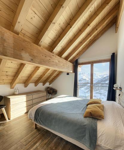 a bedroom with a large bed and wooden ceilings at Chalet Le Mauntenrojji - skis aux pieds in La Toussuire