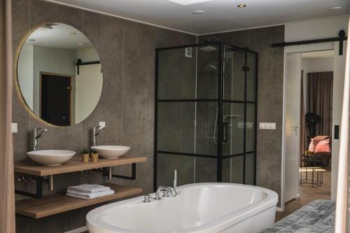 een badkamer met een bad en een grote spiegel bij Panorama lodge with wellness and hottub 2 p. in Rijssen