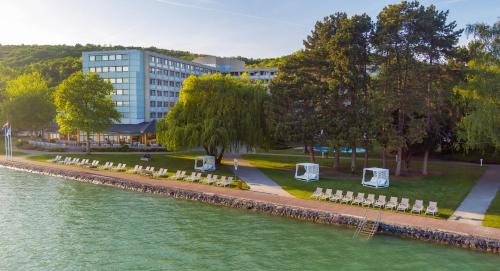 a row of white tables and chairs next to a river at Hotel Club Tihany in Tihany