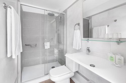 a white bathroom with a toilet and a shower at MUR Apartamentos Buenos Aires Gran Canaria in Playa del Ingles