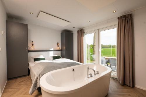 een wit bad in een slaapkamer met een bed bij Panorama lodge with jacuzzi 2 p. in Rijssen