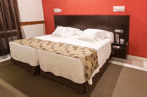 a bedroom with a large bed with a red wall at Pintor El Greco in Toledo