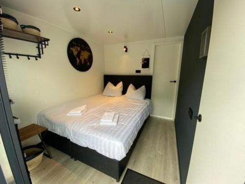 a bedroom with a bed with white sheets and a clock at Houseboat Marina Mookerplas 4-6 persons roof terrace in Plasmolen