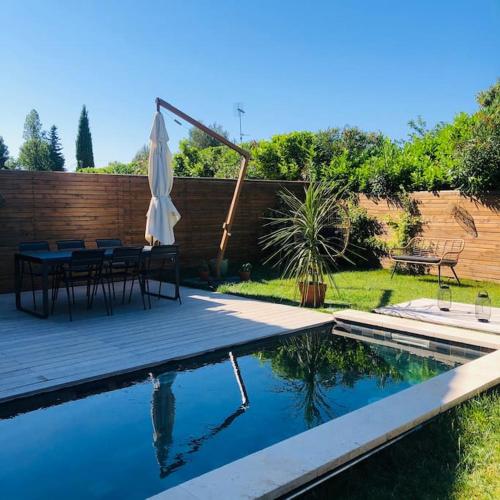 une piscine avec une table et un parasol dans l'établissement Villa Piscine - 5 min du centre historique d'Aix en Provence, à Aix-en-Provence