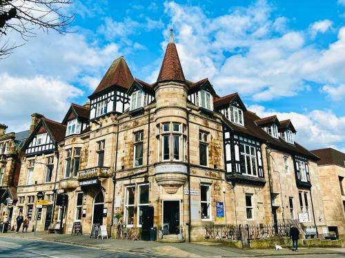 a large stone building with a turret on a street at Top floor double en-suite BR apartment central Matlock in Matlock