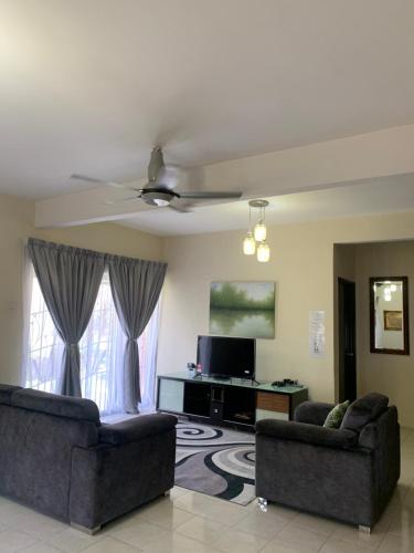 uma sala de estar com dois sofás e uma televisão em Landed 3BR near Bangi Wonderland - Wi-Fi, Netflix em Kajang