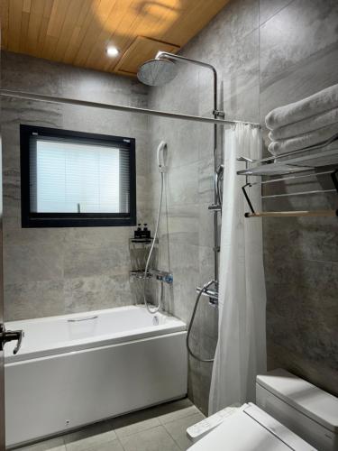 ein Badezimmer mit einer Dusche, einer Badewanne und einem WC in der Unterkunft Triple One Entire Home 慶東111私人招待所 包棟民宿 in Tainan