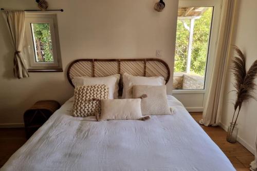 une chambre avec un lit blanc avec des oreillers et une fenêtre dans l'établissement L'Insouciant, à Graye-sur-Mer