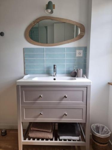 une salle de bain avec un lavabo et un miroir dans l'établissement L'Insouciant, à Graye-sur-Mer