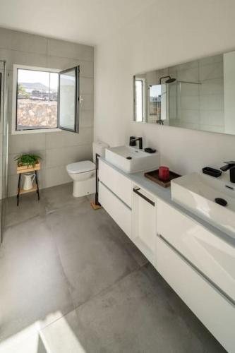 a white bathroom with two sinks and a toilet at Casa Lero in Las Breñas