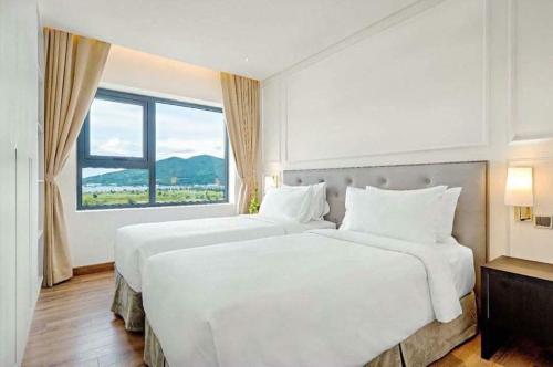 Two Bedroom with Kitchen Golden Bay Da Nang في دا نانغ: غرفة نوم بسريرين ونافذة كبيرة