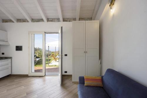 a living room with a blue couch and an open door at Studio Nido in Pompeiana