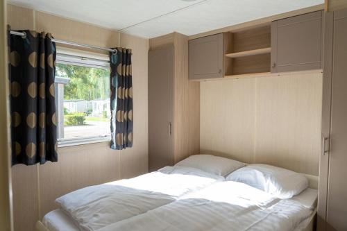 a bed in a small room with a window at Mobile home by the Regge I 4 people in Zuna