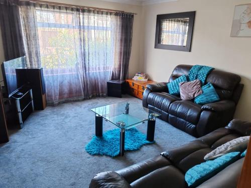 sala de estar con sofá de cuero y mesa de cristal en Wallace View - Holiday Home en Stirling