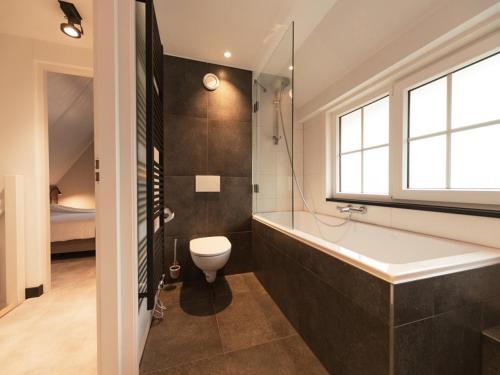 baño con bañera, aseo y ventana en Luxe villa met wellness en domotica, en Soest