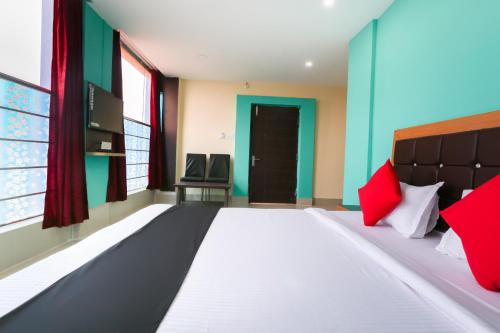 OYO Hotel Nakshatra. في Āsansol: غرفة نوم بسرير كبير ومخدات حمراء