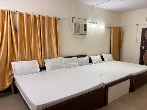 2 camas en una habitación con cortinas en Hotel Ganesh Inn en Mathura