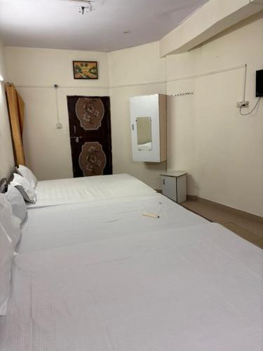 1 dormitorio con 1 cama blanca y TV en la pared en Hotel Ganesh Inn en Mathura