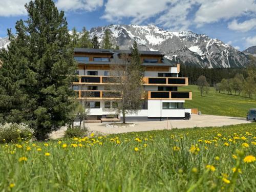 a building in front of a field of flowers at Waldrand Apartments in Ramsau am Dachstein
