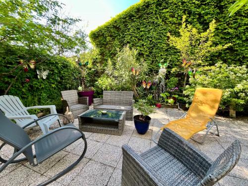 a patio with chairs and a coffee table and a hedge at Le Cosy, accès terrasse de l'établissement in Rives