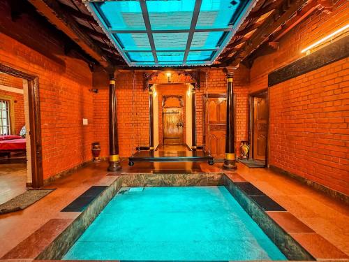 an indoor swimming pool in a room with a brick wall at Royal Experiences Chettinad Sea Side Villa, Kanathur ECR Chennai in Chennai