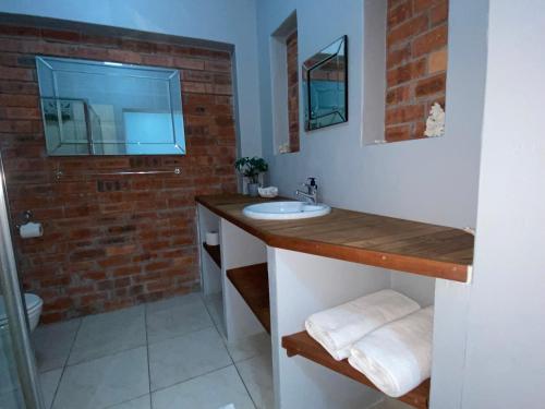 a bathroom with a sink and a brick wall at Bel Air 1 in Grabouw