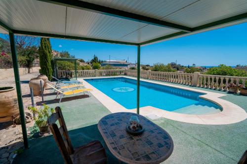 a swimming pool with a table and an umbrella at Casas Rurales Delfos in Villajoyosa