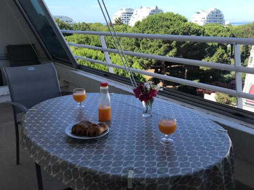 une table avec une assiette de nourriture et deux verres de jus d'orange dans l'établissement Les jardins du couchant, à La Grande Motte