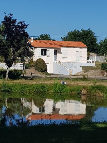 a white house next to a body of water at Maison vacances vendee in Saint-Étienne-du-Bois