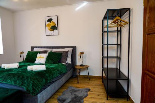 um quarto com uma cama verde e uma prateleira em Somos Lux Vendégház em Somoskőújfalu