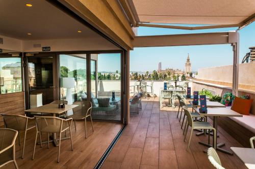 a balcony with tables and chairs and a view of the city at Hotel Alcázar in Seville