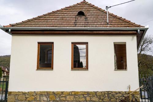 a house with three windows and a stone wall at Somos Lux Vendégház in Somoskőújfalu