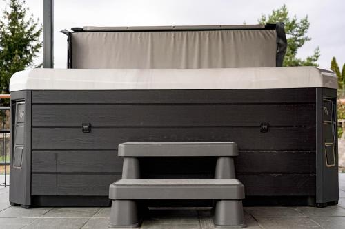 a black and white bed with a bench at Somos Lux Vendégház in Somoskőújfalu
