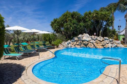 a pool with chairs and umbrellas at a resort at Villa Vacanze Paradiso - Oasi di Tranquillità con Piscina e Giardino a 10 min dal mare in Neviano