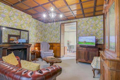 a living room with a leather couch and a television at Villa Tagini Between Story And Elegance - Happy Rentals in Brovello-Carpugnino