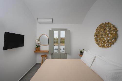 a bedroom with a bed and a mirror and a tv at Aegean Diamonds Luxury Suites in Monolithos