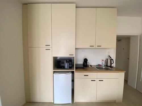 a small kitchen with white cabinets and a refrigerator at Bella Apartments Brno in Brno
