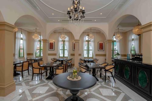 Un restaurante con mesas y sillas y una lámpara de araña. en Souphattra Heritage Vientiane, en Vientiane