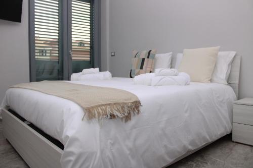 Una cama blanca con sábanas blancas y almohadas. en JOHN'S ROOMS, en Villa D'agri