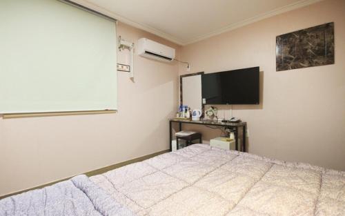 1 dormitorio con 1 cama y TV de pantalla plana en Grand Motel, en Busan