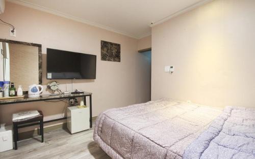 1 dormitorio con 1 cama y TV en la pared en Grand Motel, en Busan
