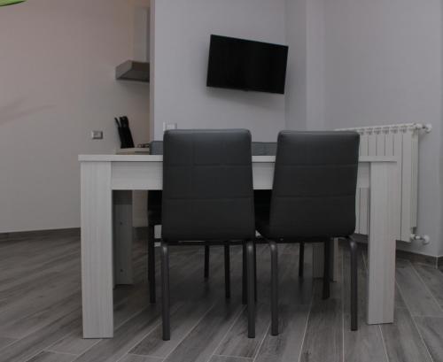 a dining room table with black chairs and a television at JOHN'S ROOMS in Villa D'agri