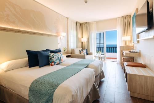 a hotel room with a bed with a view of the ocean at Hotel Jardín Tecina in Playa de Santiago