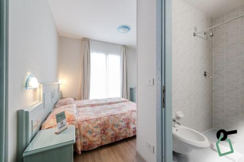 Schlafzimmer mit einem Bett, einer Badewanne und einem Waschbecken in der Unterkunft HOTIDAY Hotel Jesolo Lido in Lido di Jesolo