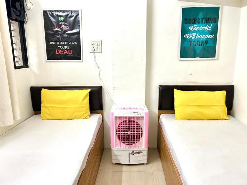 Duas camas num pequeno quarto com uma ventoinha. em Procida Hostel by Zero Jhanjhat em Pune