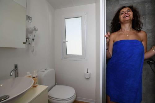 Una mujer con un vestido azul parada en un baño en Don Antonio Glamping Village, en Giulianova